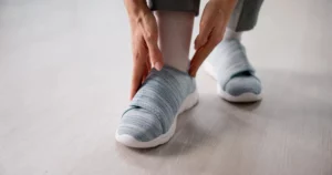 Person wearing supportive footwear while checking their feet as part of a daily diabetic foot care routine